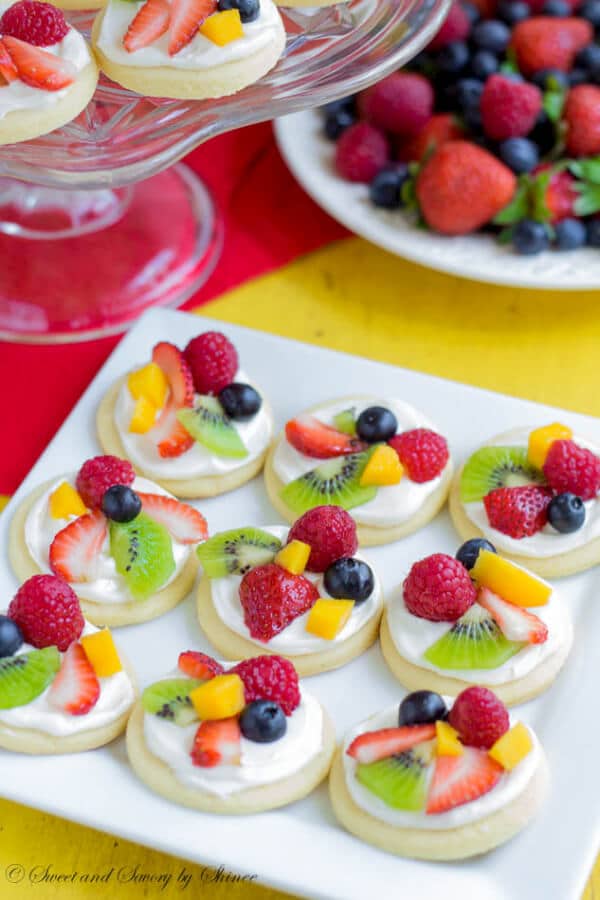Summer classic in bite-size! These mini fruit pizzas are built on simple soft sugar cookies and topped with white chocolate cream cheese filling and colorful fresh fruits.