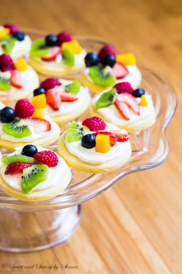 Summer classic in bite-size! These mini fruit pizzas are built on simple soft sugar cookies and topped with white chocolate cream cheese filling and colorful fresh fruits.