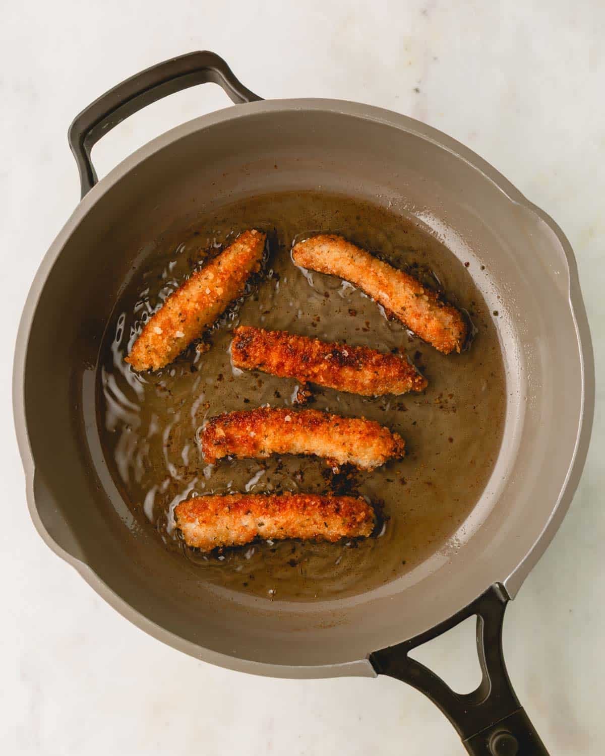 Cooked pork strips in a skillet.