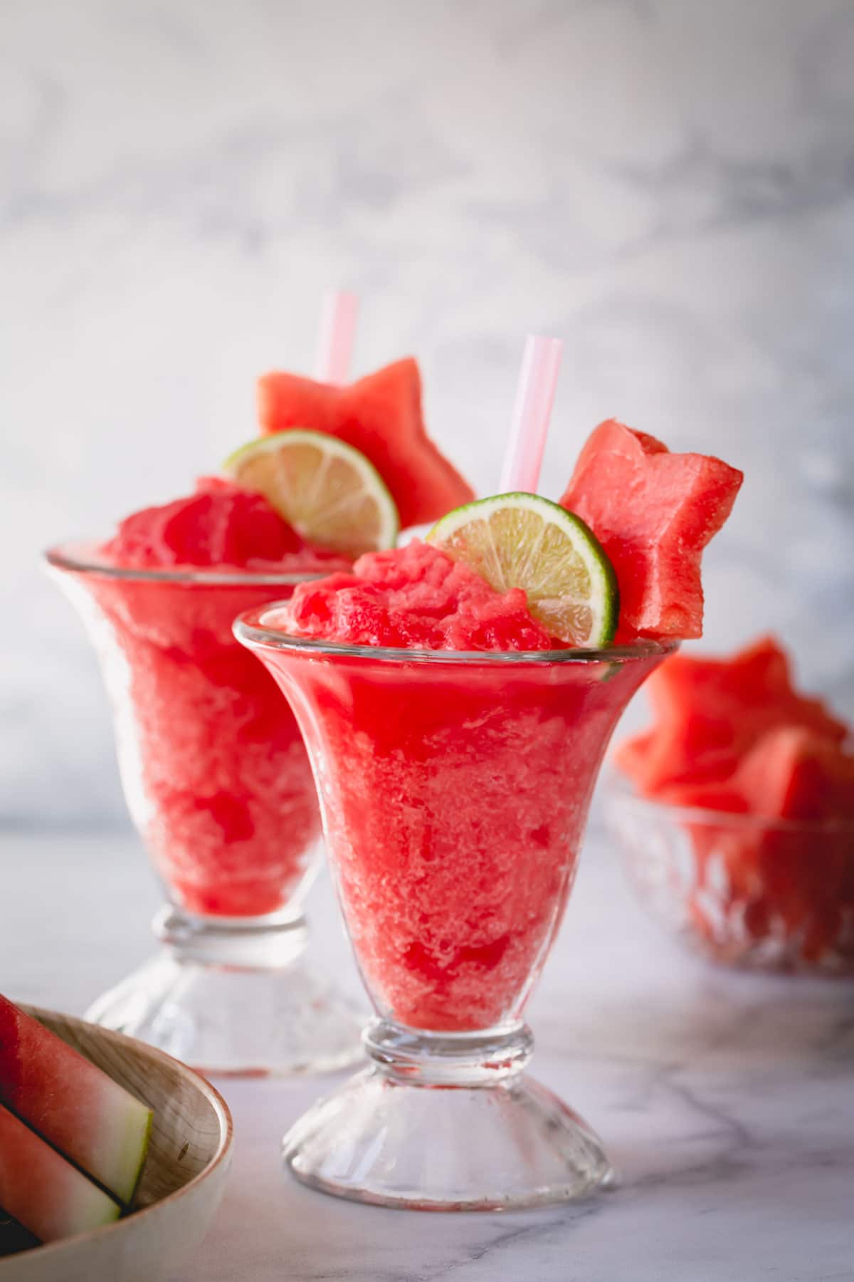 2 glasses of frozen watermelon daiquiri garnished with slice of lime and watermelon star.