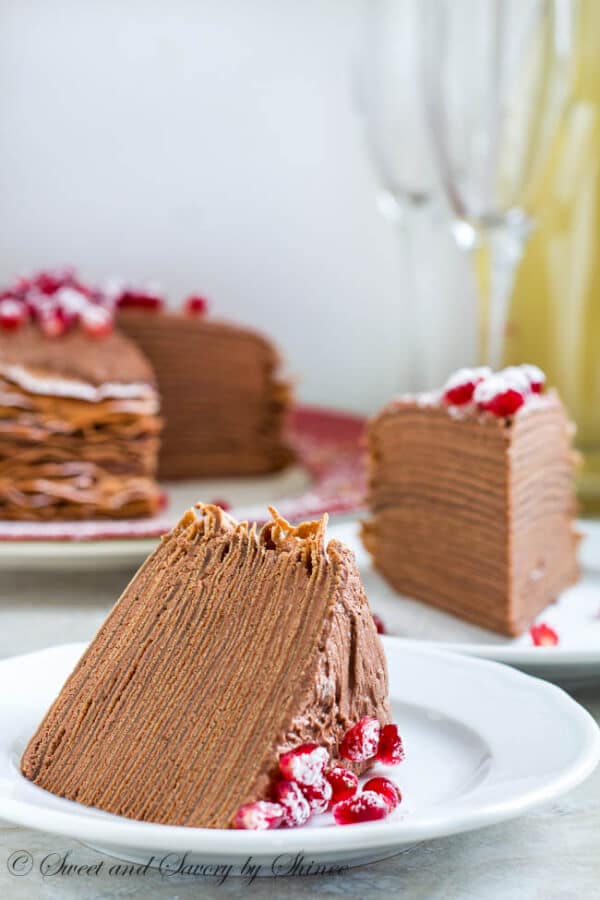 This beautiful chocolate mousse crepe cake is made of 20+ layers of delicate chocolate crepes filled with rich chocolate mousse filling and topped with festive red pomegranates. 