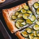 a close-up shot of zucchini tart on a baking sheet.