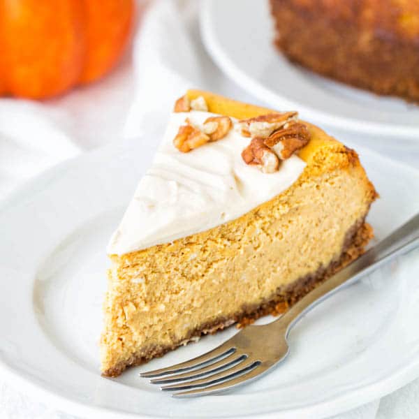 A slice of pumpkin cheesecake with maple pumpkin whipped cream frosting.