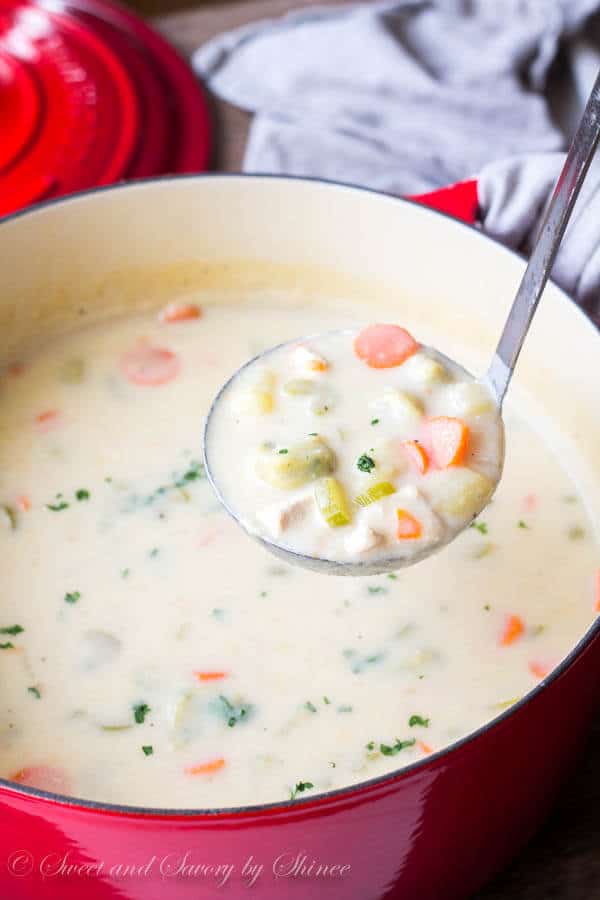 A ladle lifting a scoop of knoephla soup from a pot.