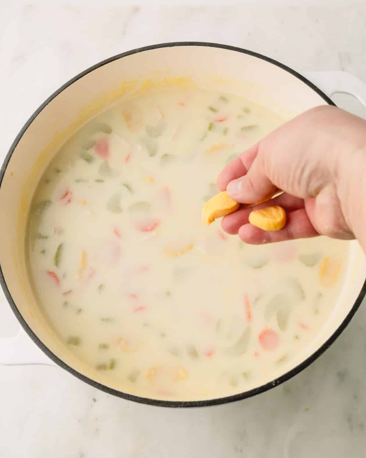 Knoephla dough is being added to the soup in a Dutch oven.