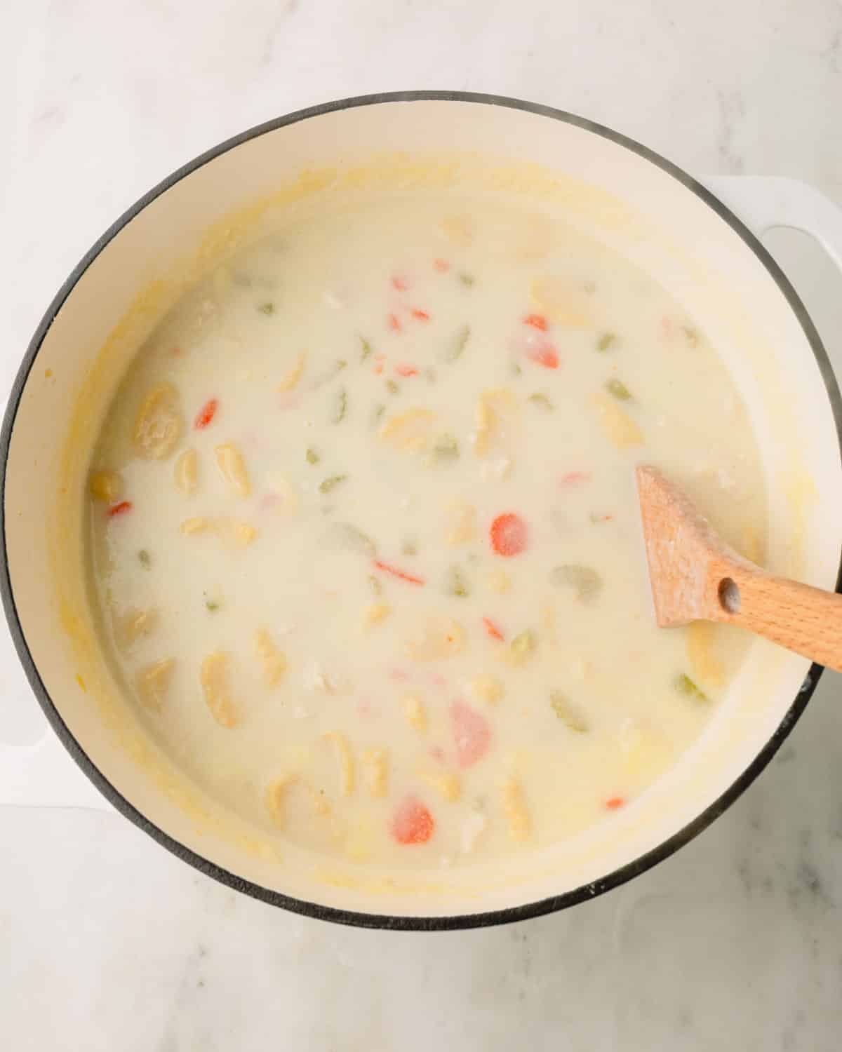 Knoephla soup is being stirred in a Dutch oven.