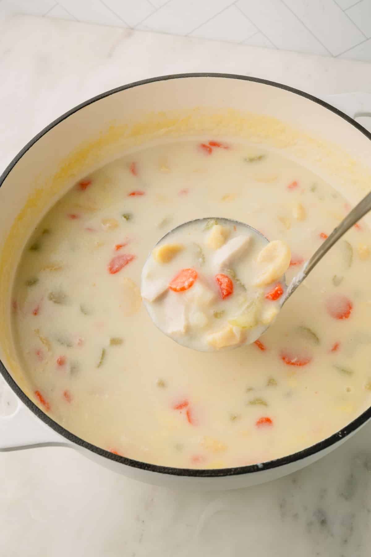 A ladle lifting a scoop of knoephla soup from a pot.