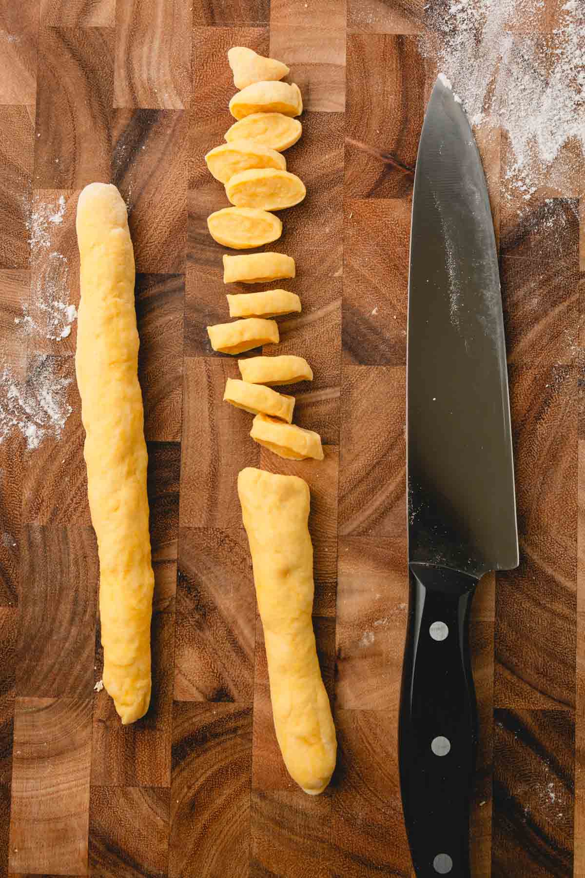 Knoephla dough is rolled into two long, skinny logs, and one log is cut into small pieces.