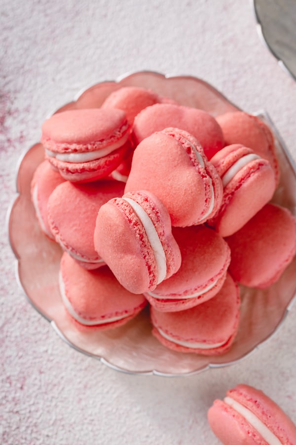 These strawberry macarons are infused with strawberry flavor in every layer (no artificial flavoring)!  So good, you wouldn't want to share these adorable little heart-shaped treats! #strawberrymacarons #frenchmacarons 