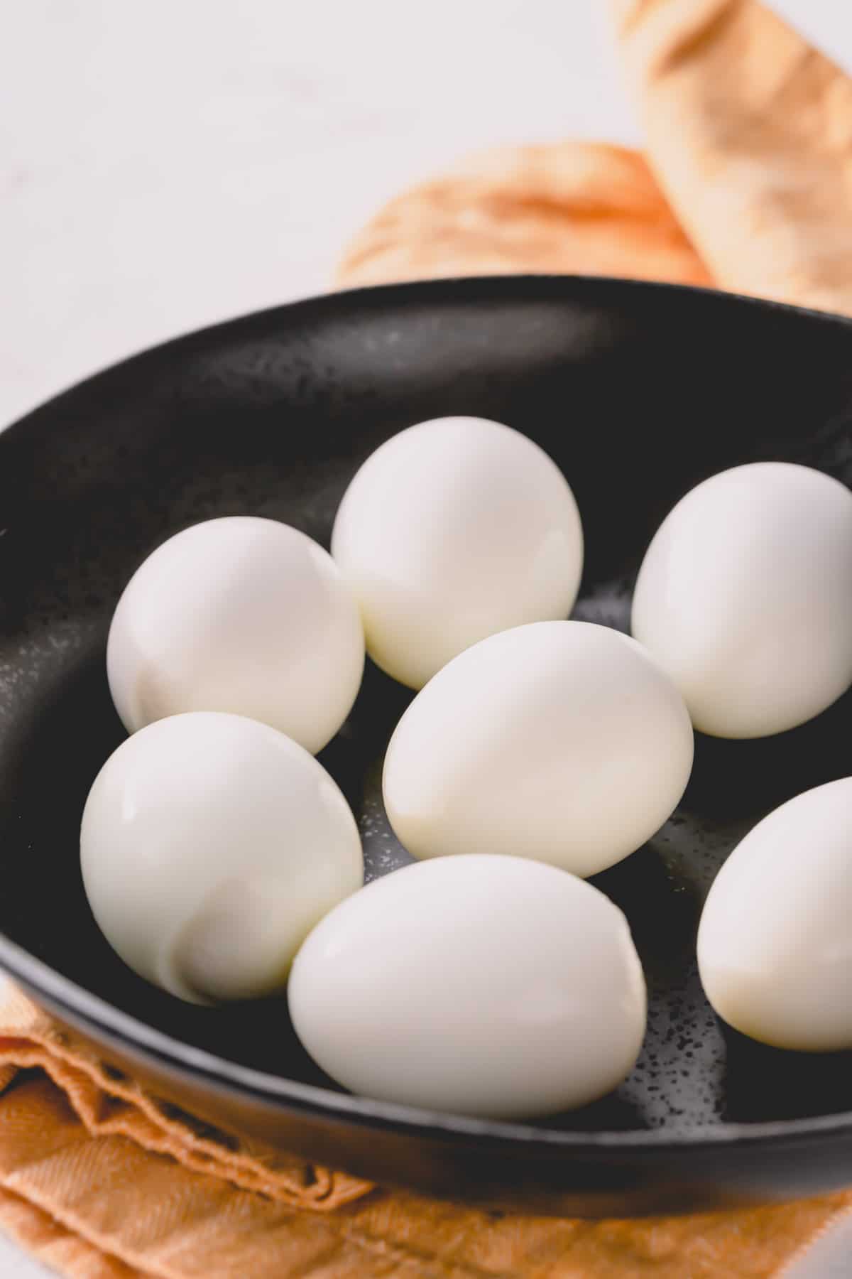 Peeled hard boiled eggs on a white plate.