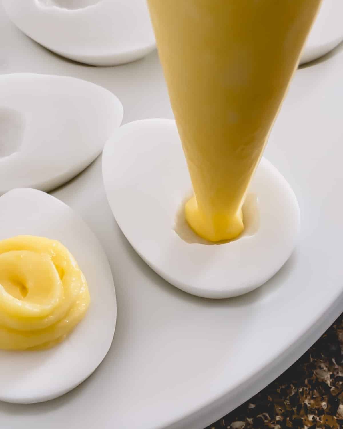 Yellow filling piped into the well on a egg-shaped coconut pudding.