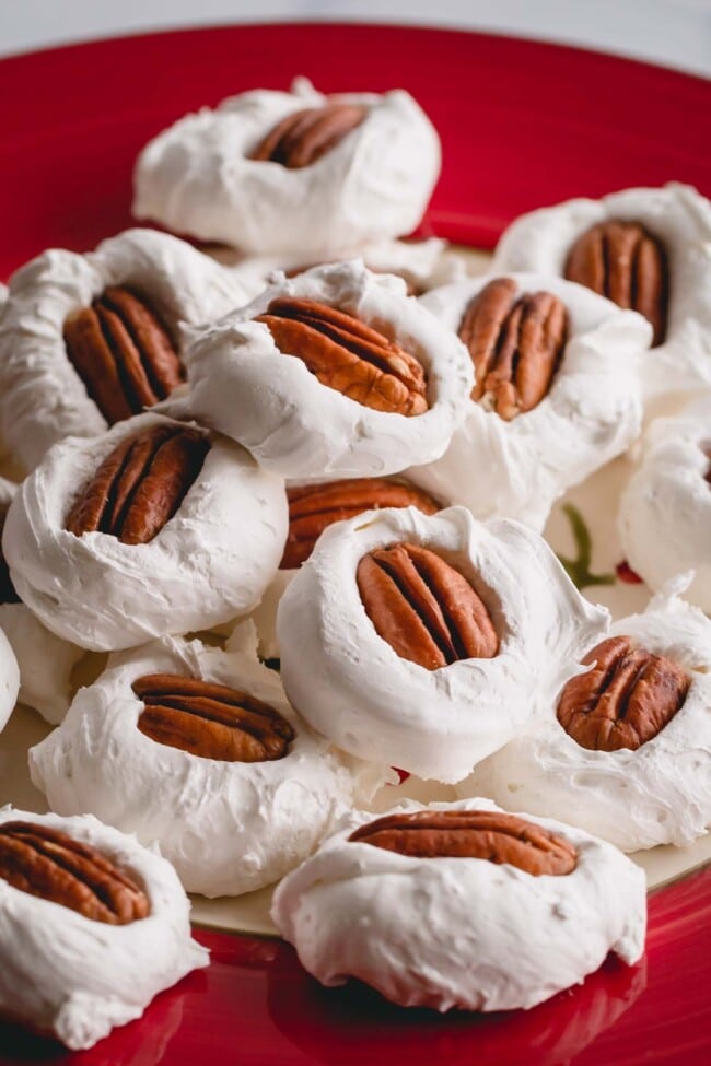 A pile of divinity with pecan halves on top on a red plate.