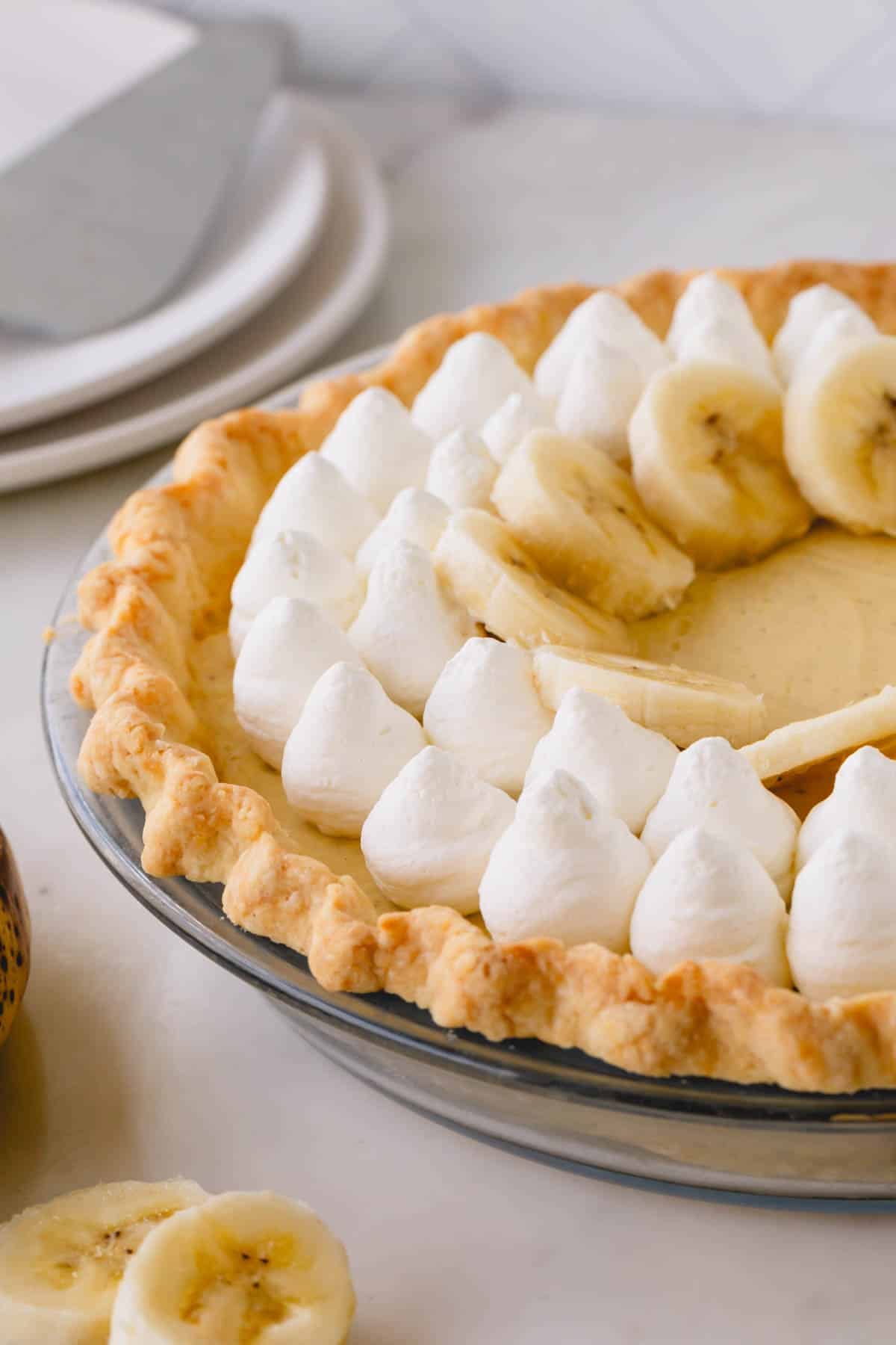 Banana cream pie decorated with dollops of whipped cream and banana slices.