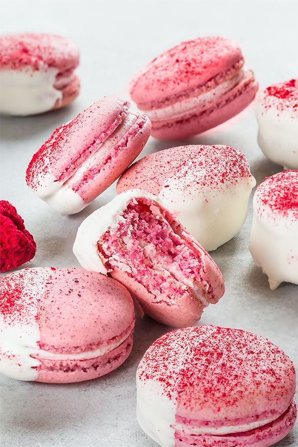 Easy to follow, detailed, step-by-step recipe for white chocolate raspberry macarons. You'll love biting into these heavenly treats bursting with flavor! #frenchmacaron #macarontutorial #raspberrymacarons #macarons