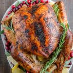 A whole lemon herb roast turkey on a serving platter.
