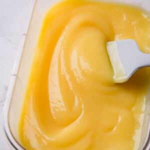 Creamy lemon curd in a clear storage container.