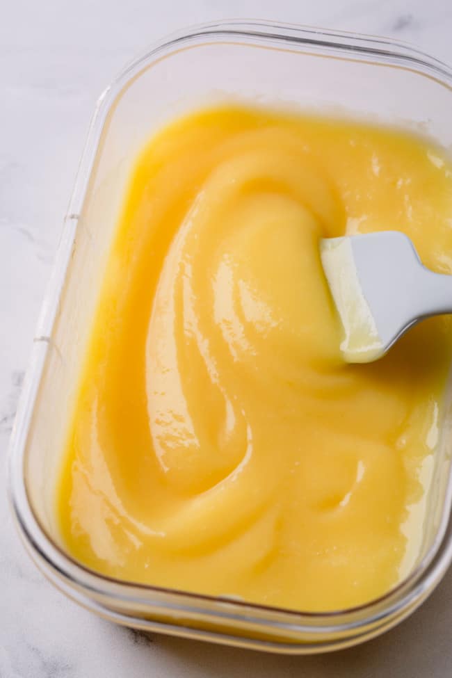 Creamy lemon curd in a clear storage container.