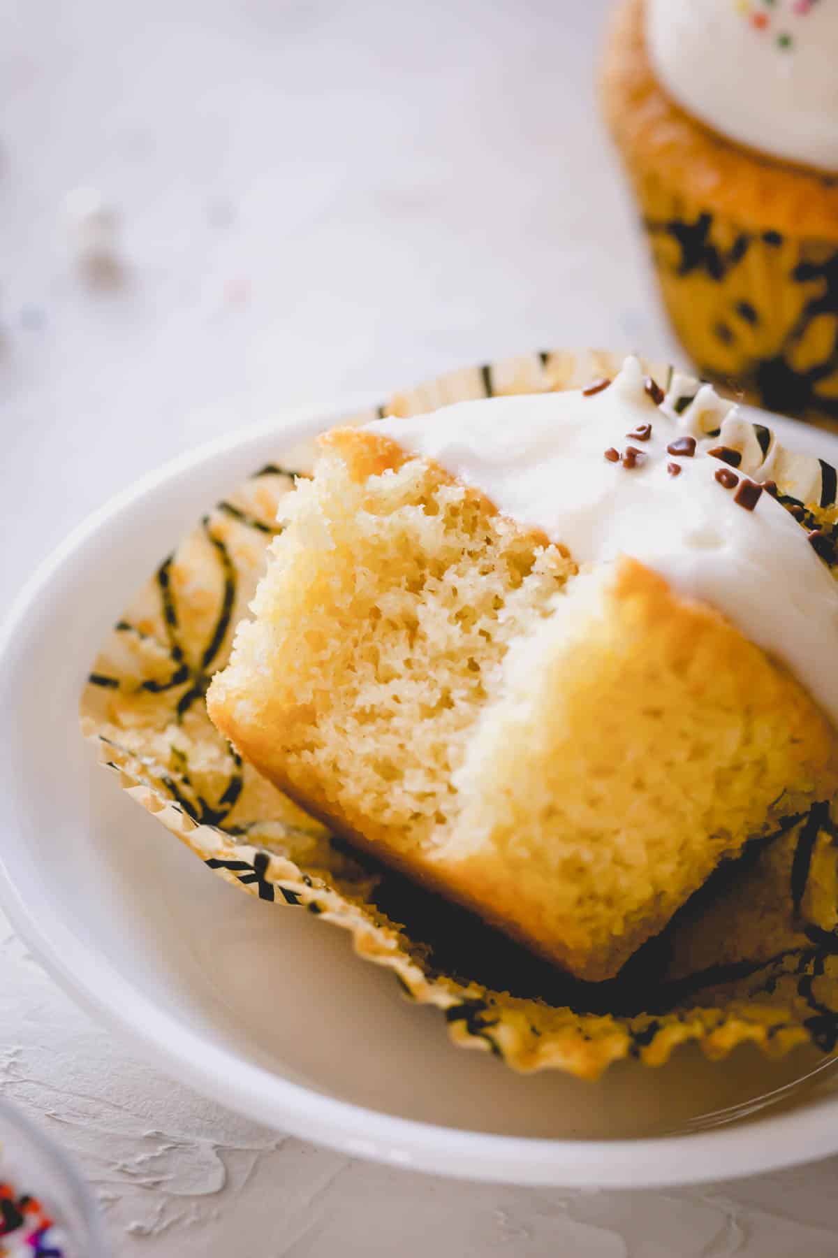 Vanilla cupcake with a bite out of it.