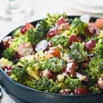 A bowl of broccoli salad with bacon and grapes.