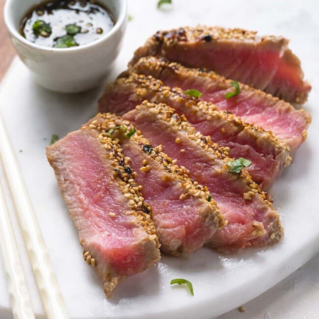 Seared and sliced ahi tuna with sesame crust on a platter.
