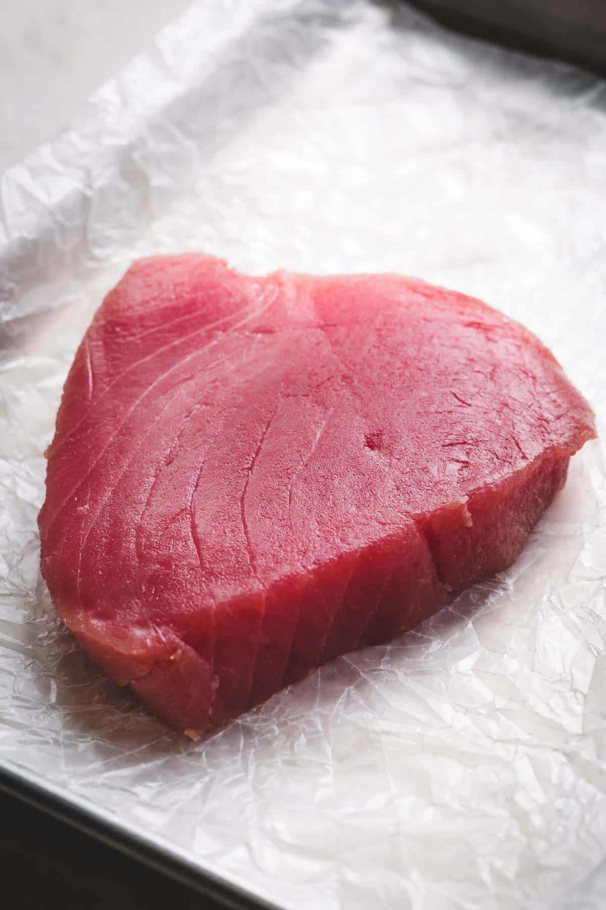 Raw ahi tuna steak on a white parchment paper.