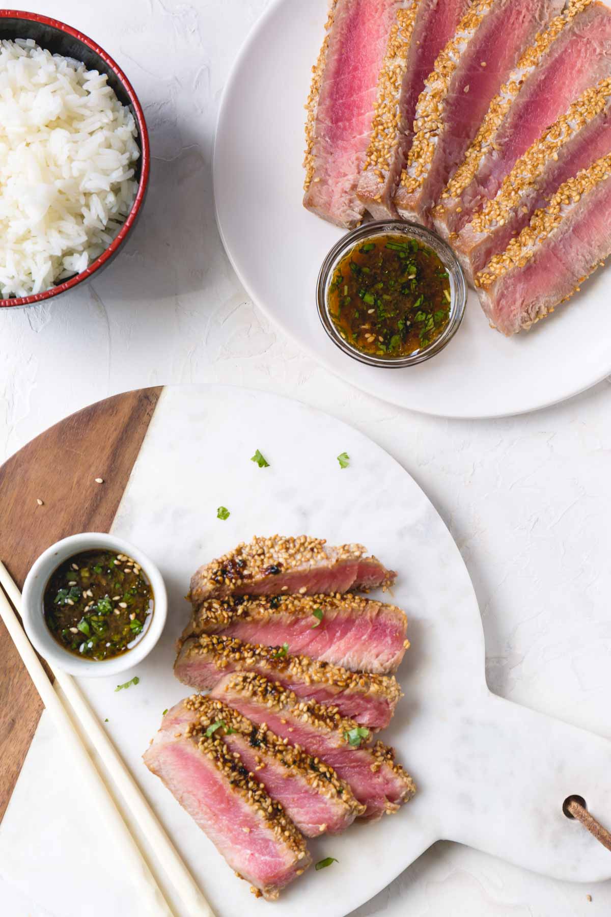 Sliced ahi tuna steak with sesame crust on a platter with dipping sauce on a side.