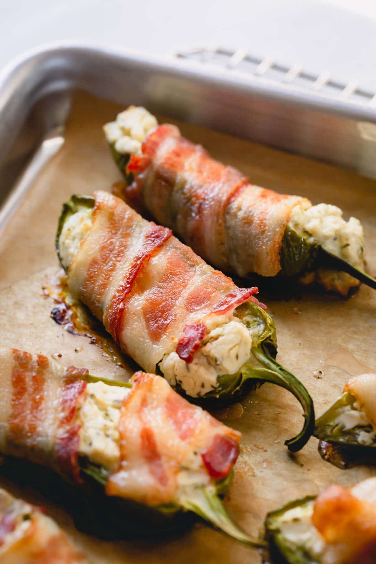 Cooked bacon jalapeno poppers on a baking sheet.