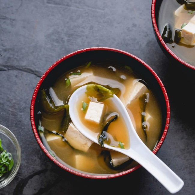 A bowl of miso soup with diced tofu and seaweed.