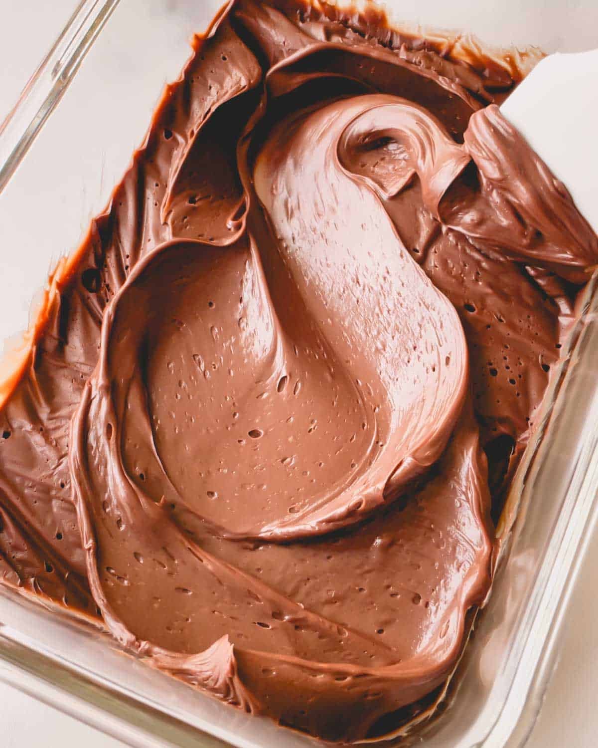 Thickened ganache in a flat container swirled with a spatula.