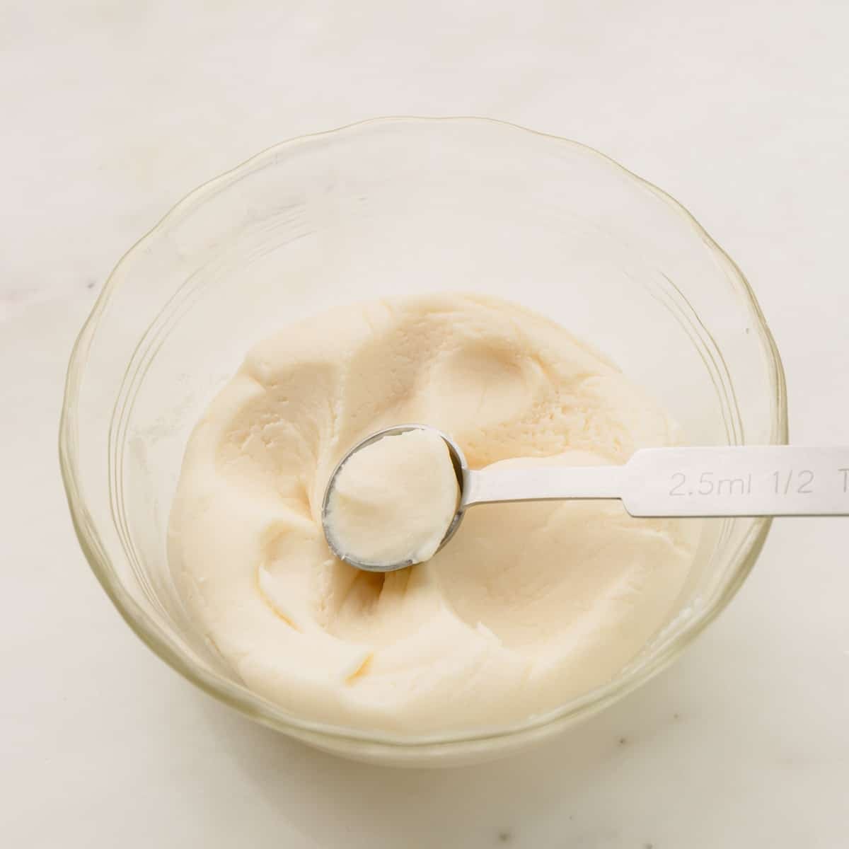 Mint candy filling in a small glass bowl with a 1/2 teaspoon measuring spoon in it.