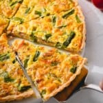 A slice of smoked salmon quiche being lifted from the whole quiche.