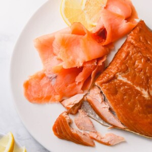 Hot smoked and cold-smoked salmons with couple of slices of lemon on a white plate. There're 2 types of smoked salmon: cold-smoked and hot smoked.