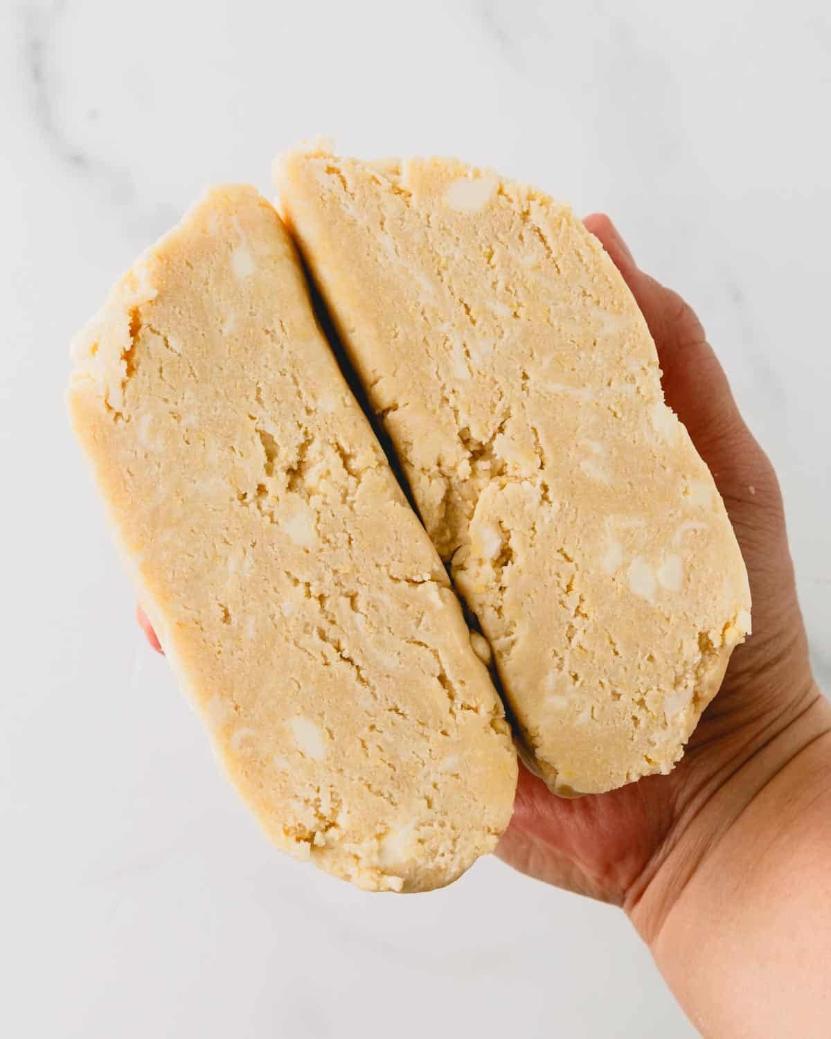Raw pie dough cut in half exposing chunks of butter throughout the dough.