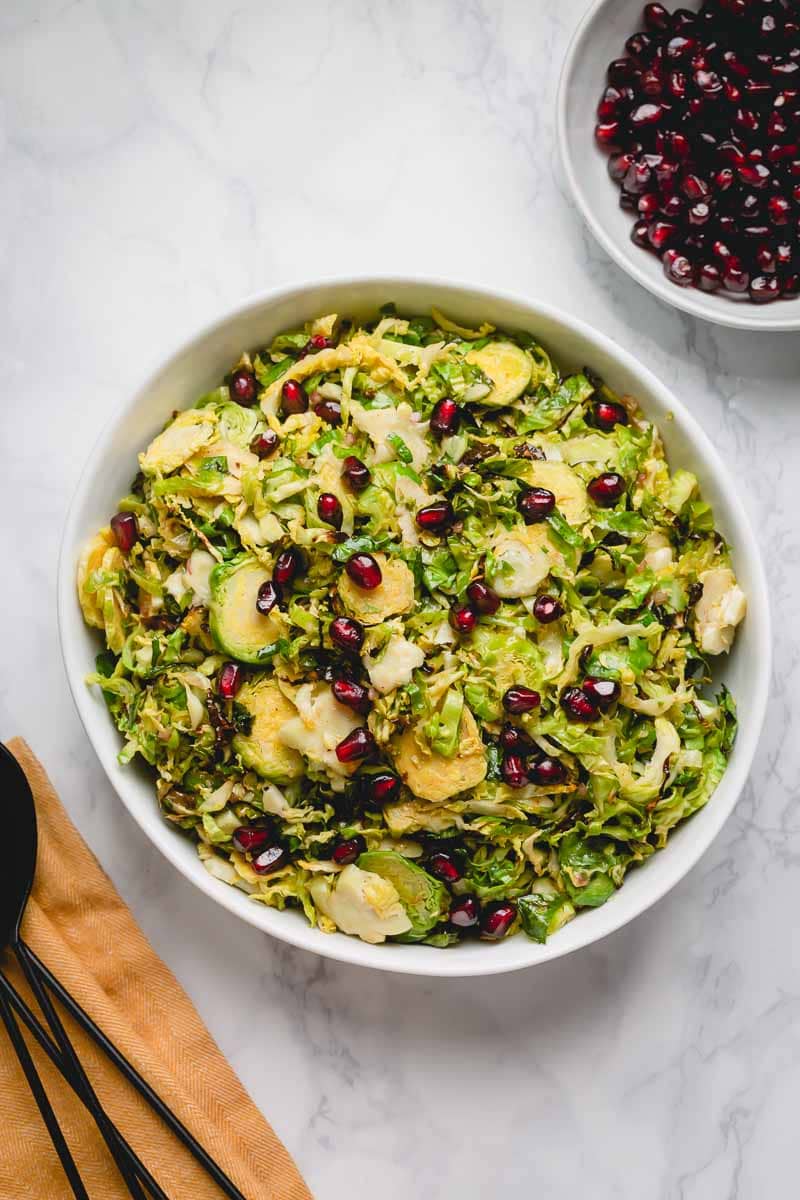 Overhead image of a bowl of roasted shaved Brussels sprouts topped with pomegranate arils.
