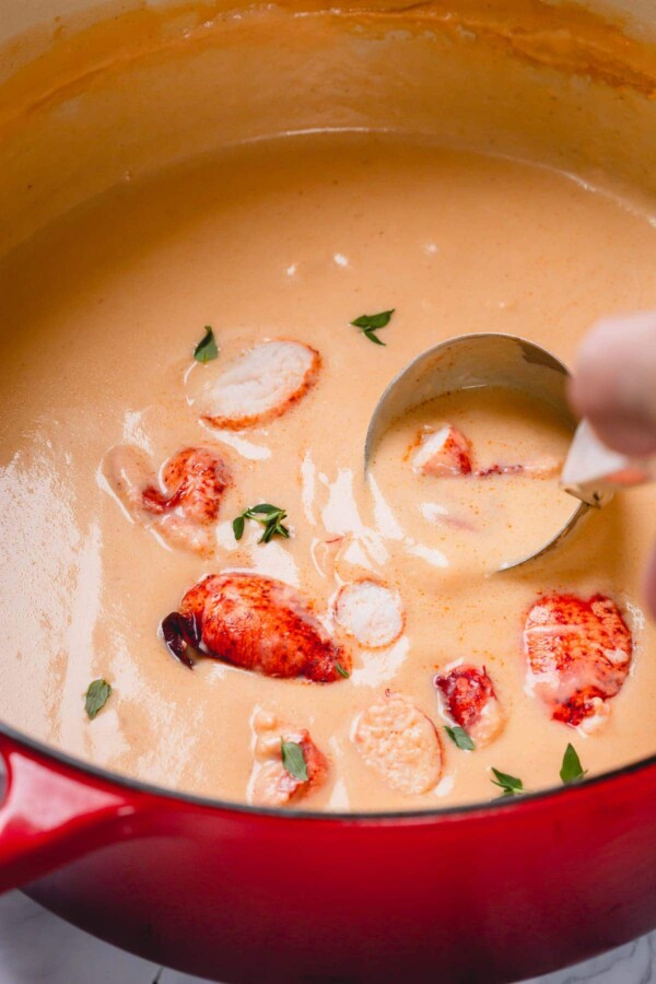 spooning lobster bisque out of a pot