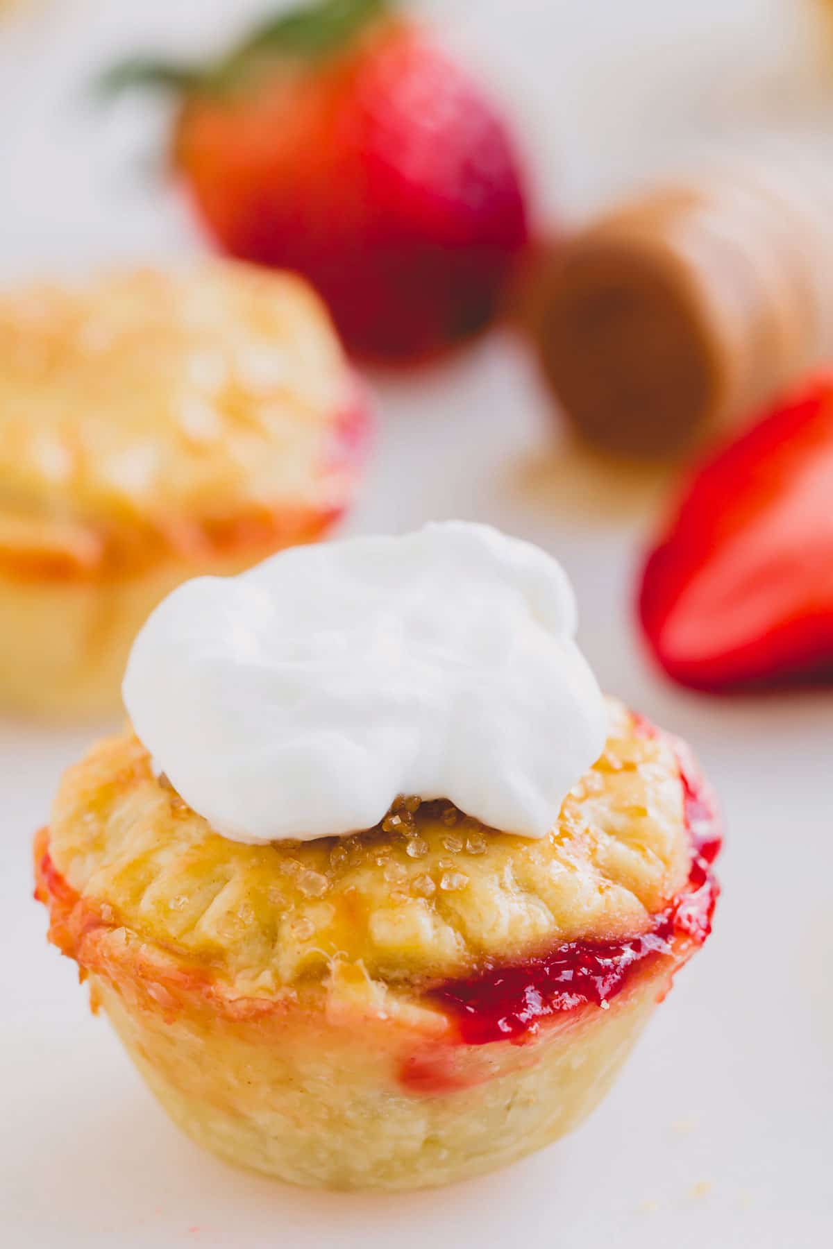 A single mini strawberry pie topped with yogurt cream on top