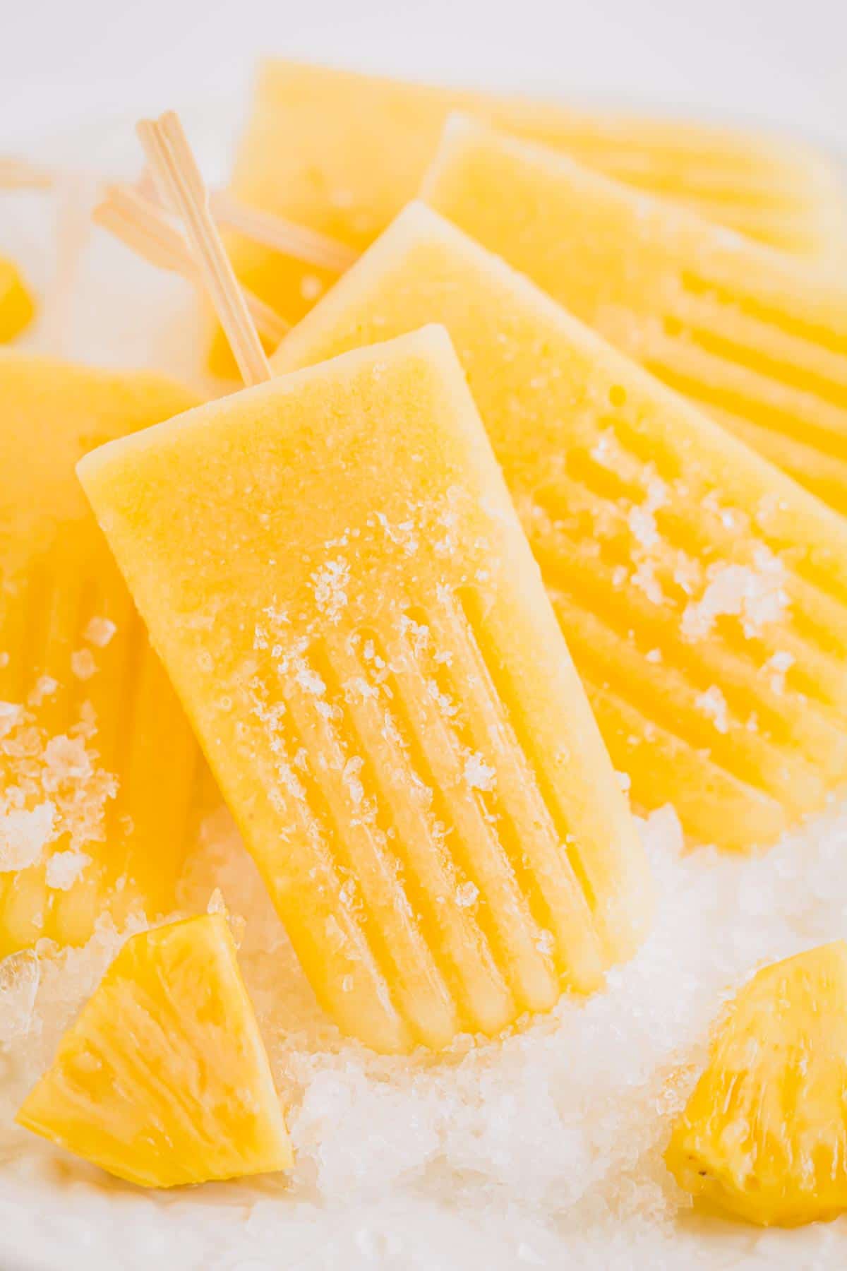 Handful of pineapple popsicles on crushed ice.