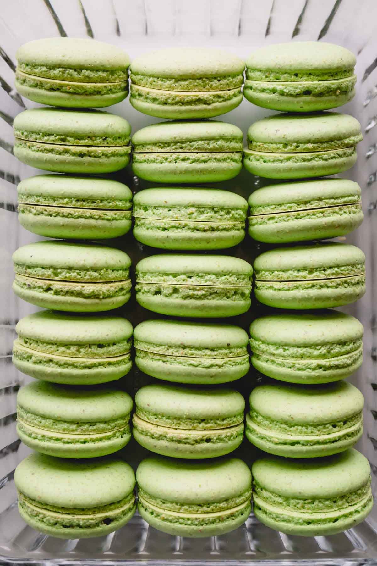 Paired pistachio macaron shells in a glass container.