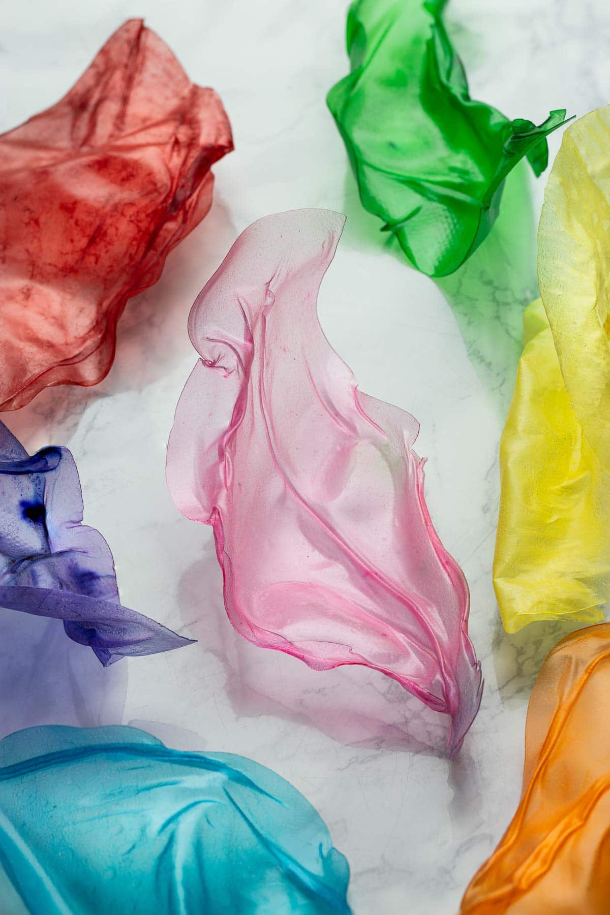 Pink rice paper sail in the center with other rainbow colored rice paper sails around it.