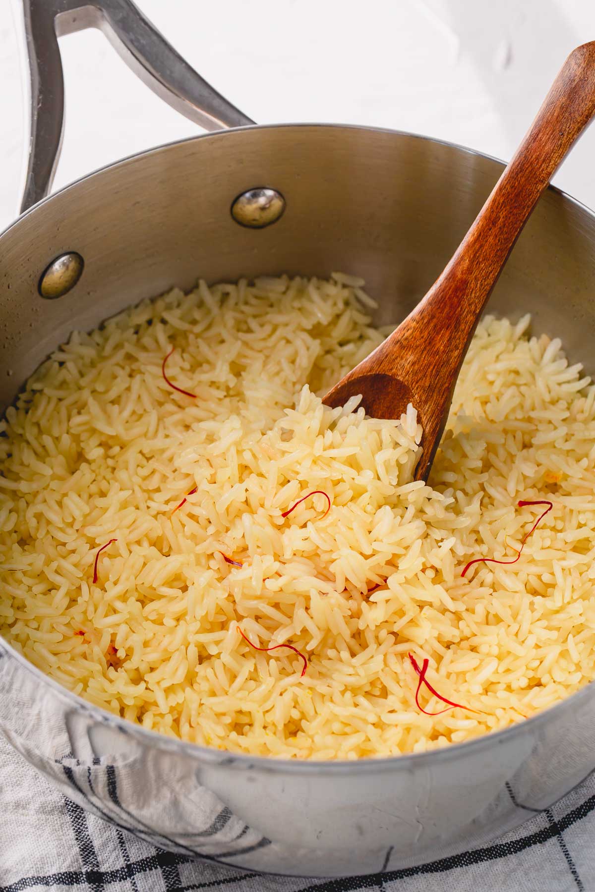 cooked saffron rice in skillet with wooden spoon