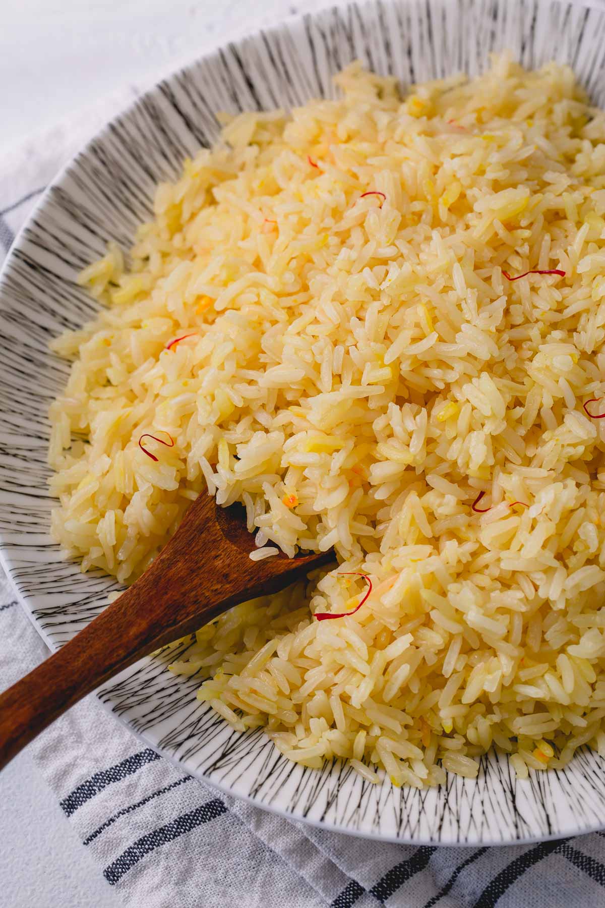 Saffron rice in bowl with wooden spoon
