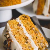Close-up shot of a slice of carrot cake on a white plate.