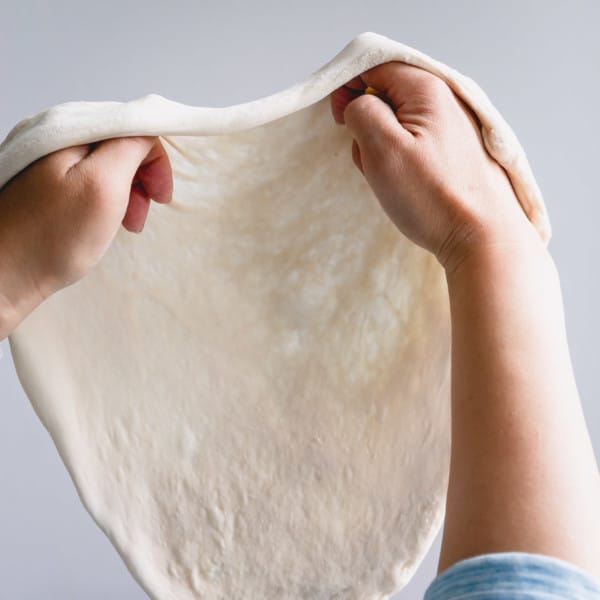 Stretching pizza dough with 2 hands.