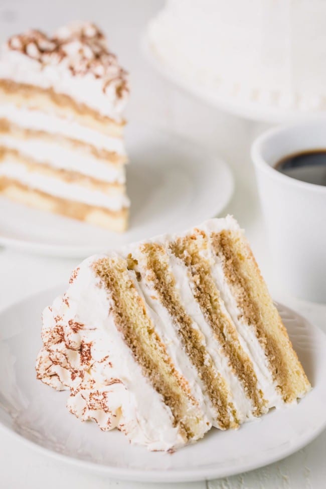 A slice of tiramisu layer cake on a white plate.