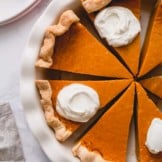 Overhead shot of sliced pumpkin pie in a pie dish.