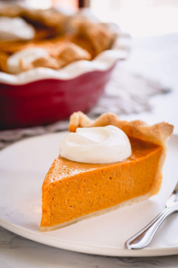 A slice of pumpkin pie on a white plate.