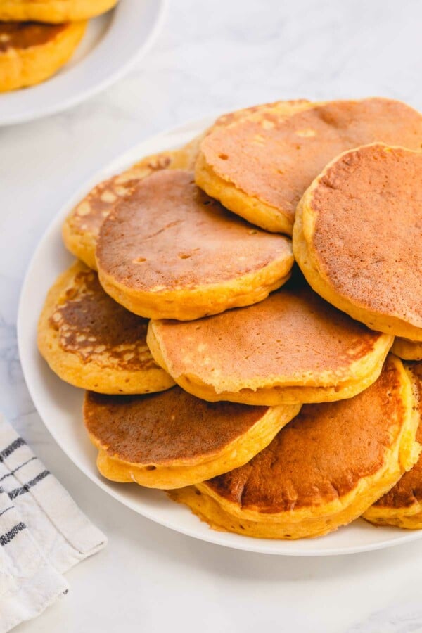 A pile of pumpkin pancakes on a serving platter.