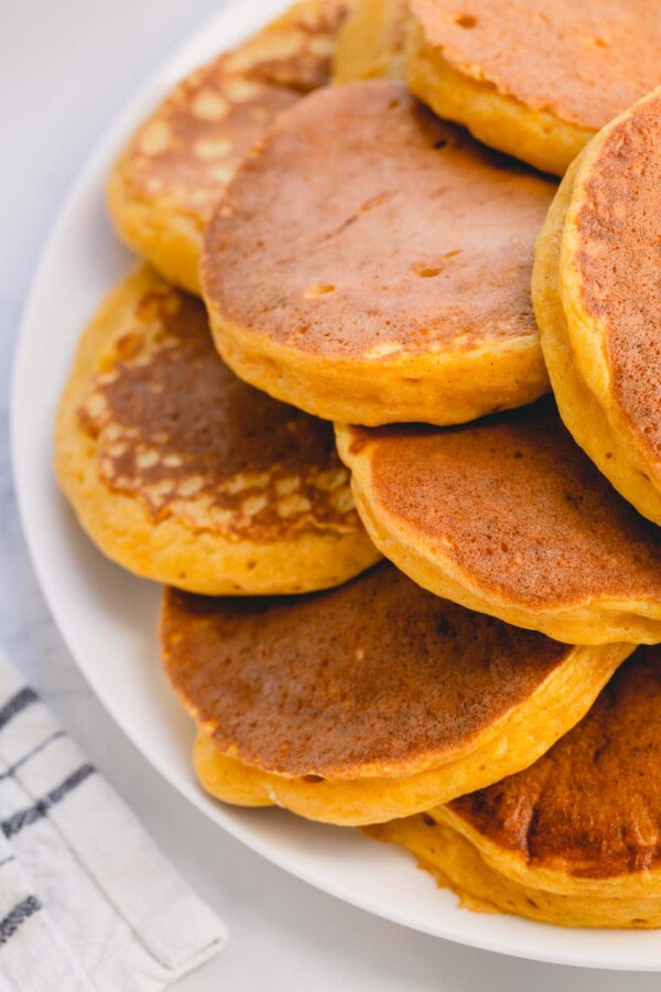 A pile of pumpkin pancakes on a serving platter.