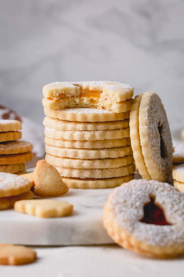 Stack of linzer cookies and a bitten cookie.