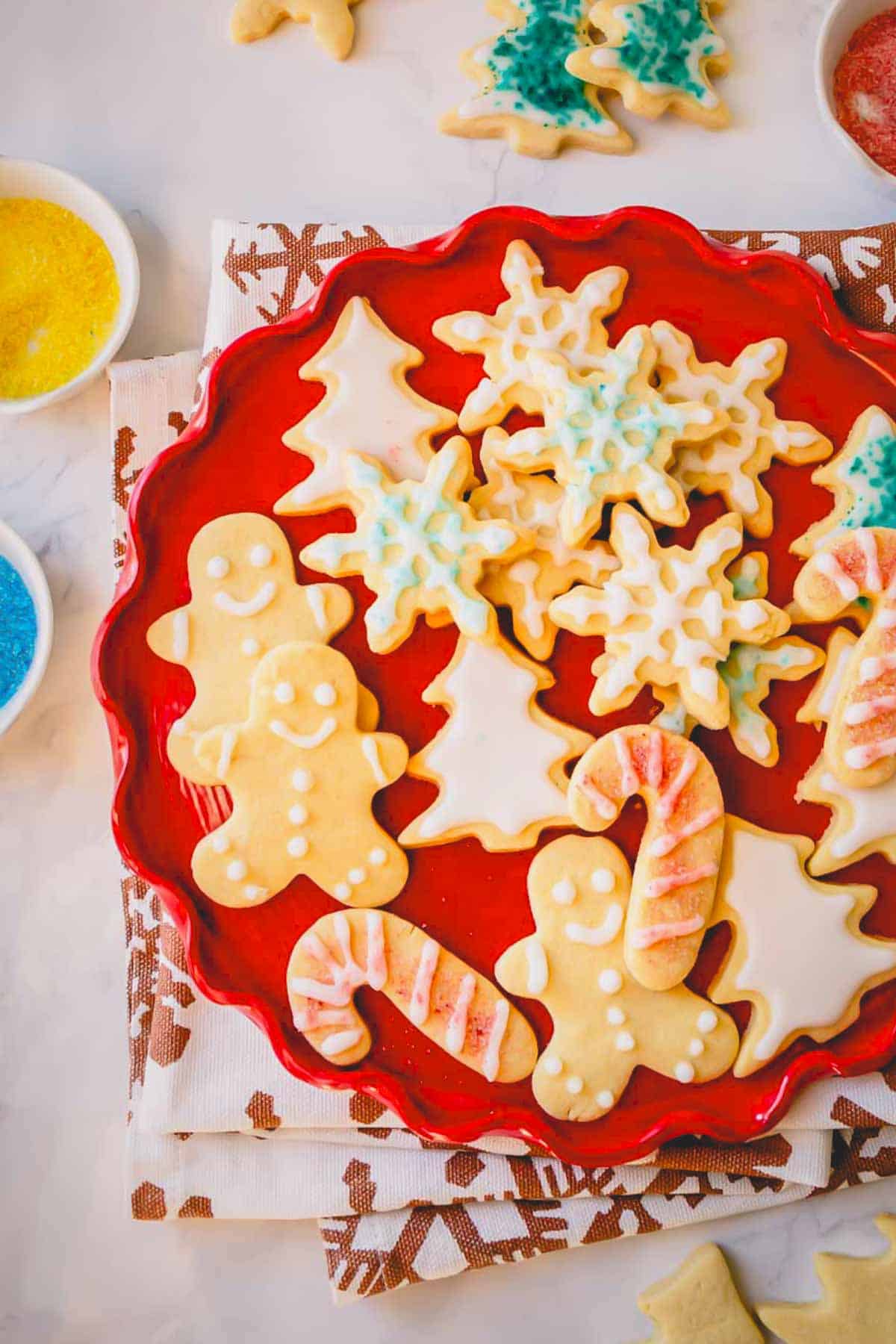 A red plate full of decorated christmas sugar cookies.